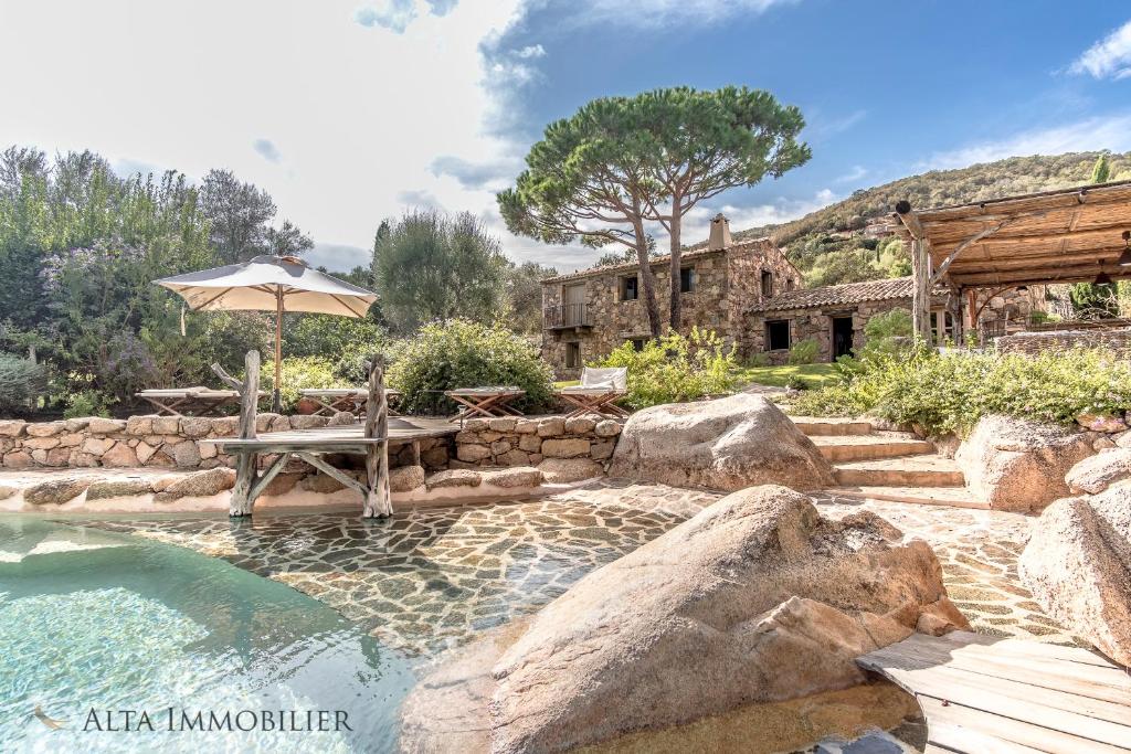 uma piscina com um banco e um guarda-sol em Villa Serenita Pallombaggia em Porto-Vecchio