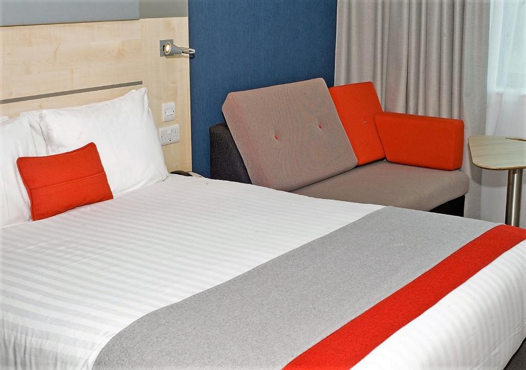 a hotel room with a bed and a chair at Holiday Inn Express Ramsgate – Minster by IHG in Minster