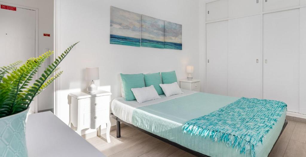 a white bedroom with a large bed with blue sheets at APARTAMENTO COR DO MAR - Sunny, Clean and spacious apartment with sea view, in Alvor - very close walking distance to the beach and Alvor Village in Alvor