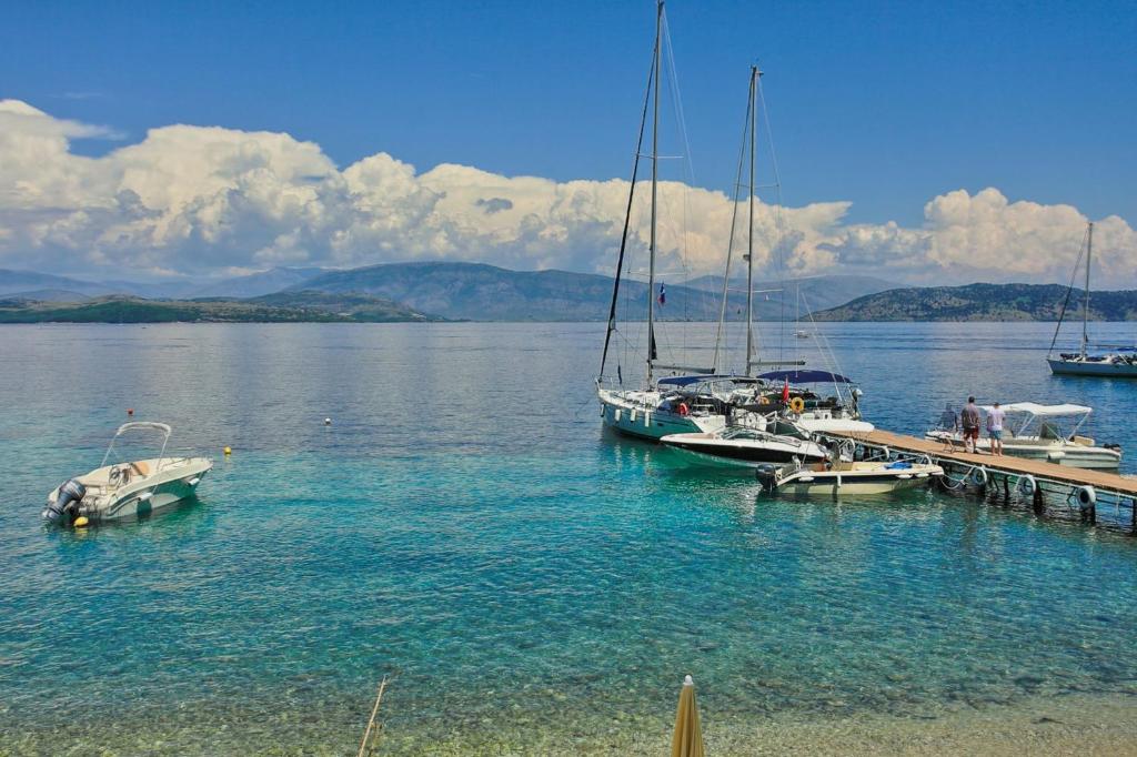a group of boats docked at a dock in the water at Olgas Cottage: Stone house on the beach in Kéntroma