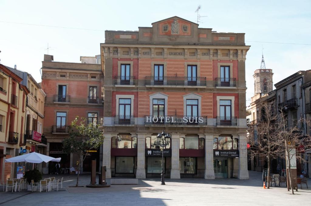a large brick building with a hotel sits on a street at Hotel Suís in Sant Celoni