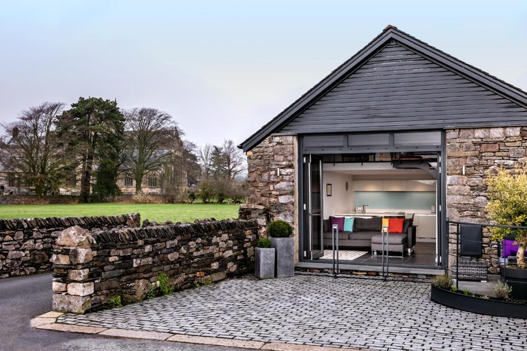 a building with a stone wall and a patio at The Old Roller Shed in Cartmel