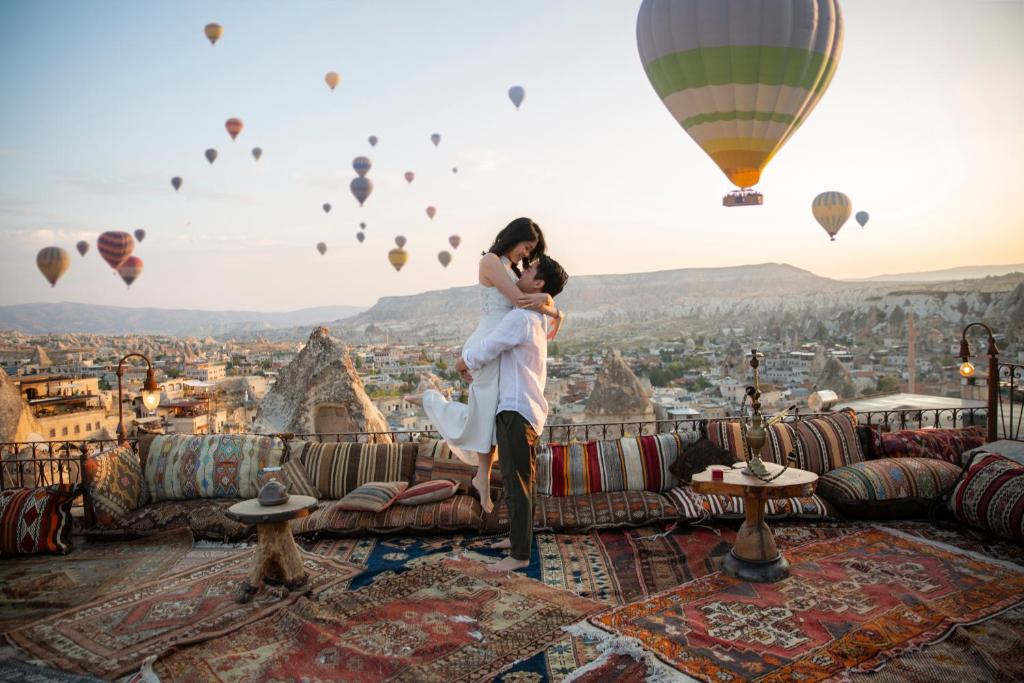 um casal em cima de um sofá com balões de ar quente em Koza Cave Hotel em Goreme