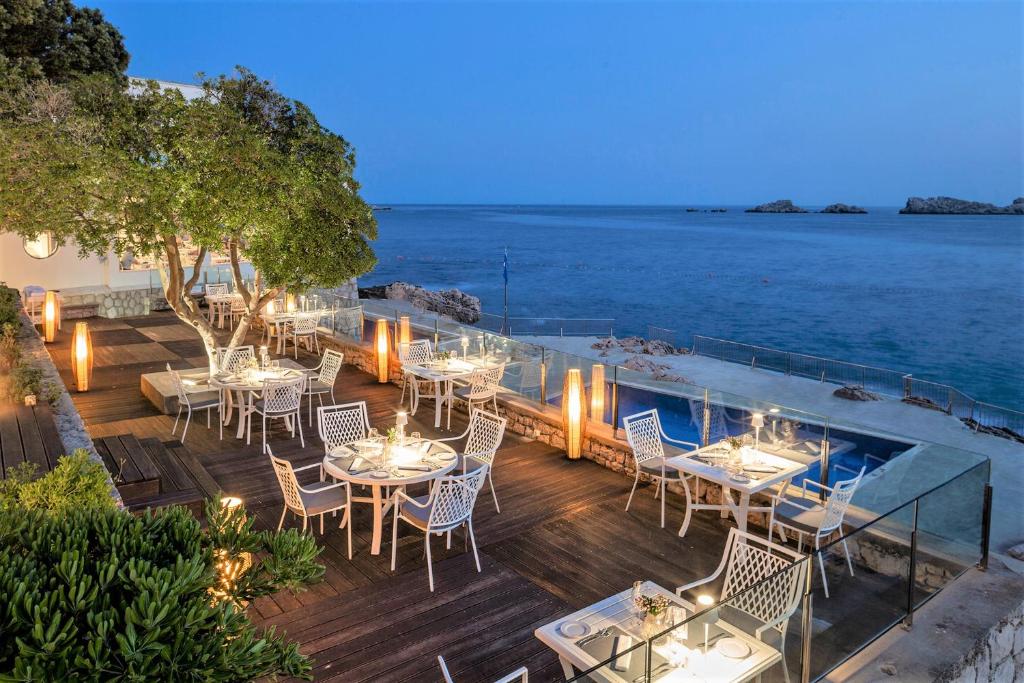 an outdoor dining area with tables and chairs and the ocean at Royal Neptun Hotel in Dubrovnik