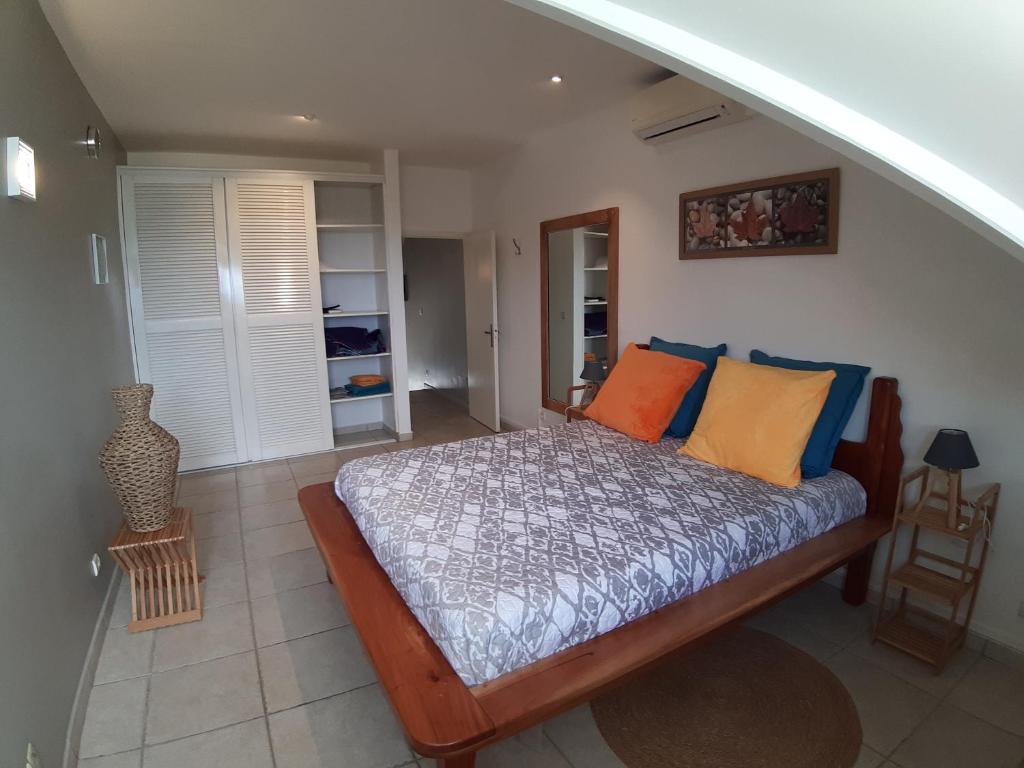 1 dormitorio con 1 cama con almohadas de color naranja y azul en La Kaz du Lagon, en Le Gosier