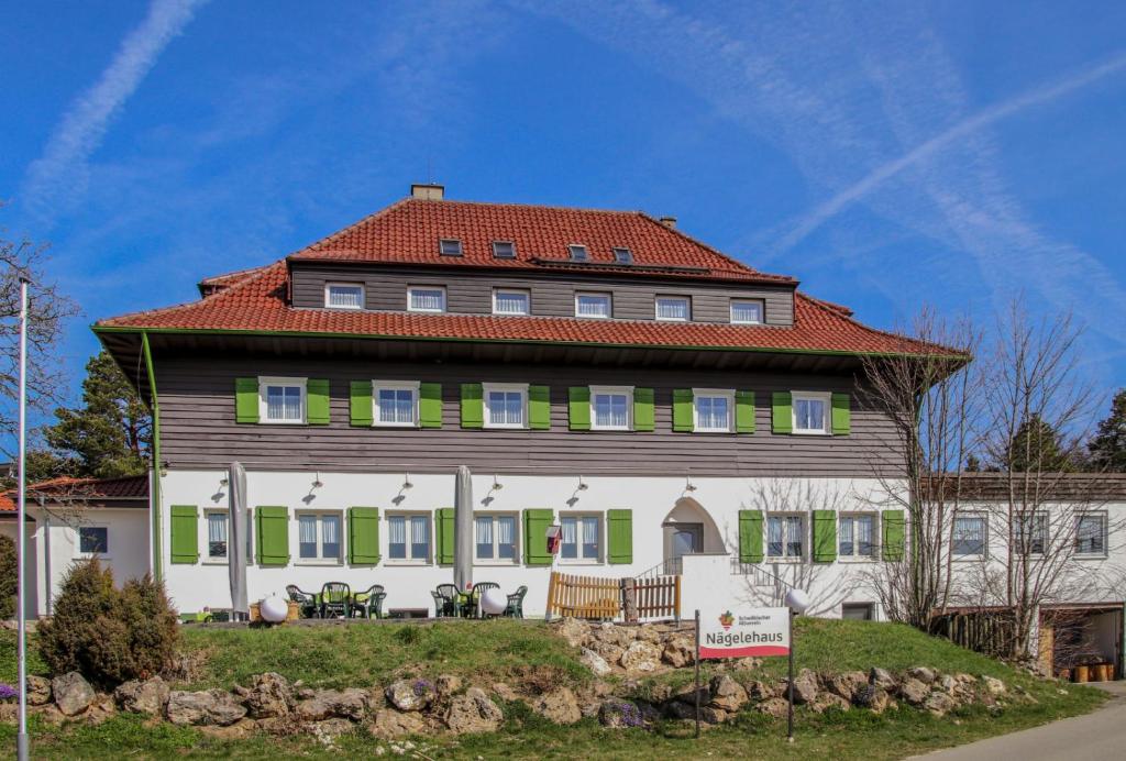 a large house with a red roof and green shutters at Höhengasthof Wanderheim Nägelehaus in Albstadt