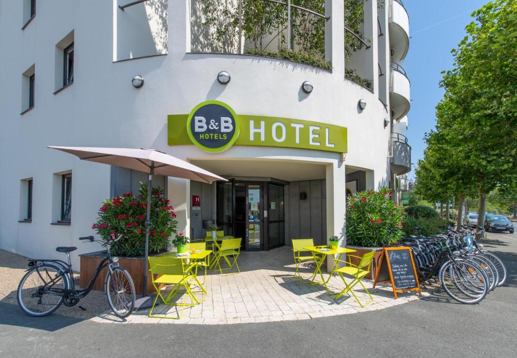 a hotel with yellow tables and chairs in front of a building at B&B HOTEL La Rochelle Centre in La Rochelle