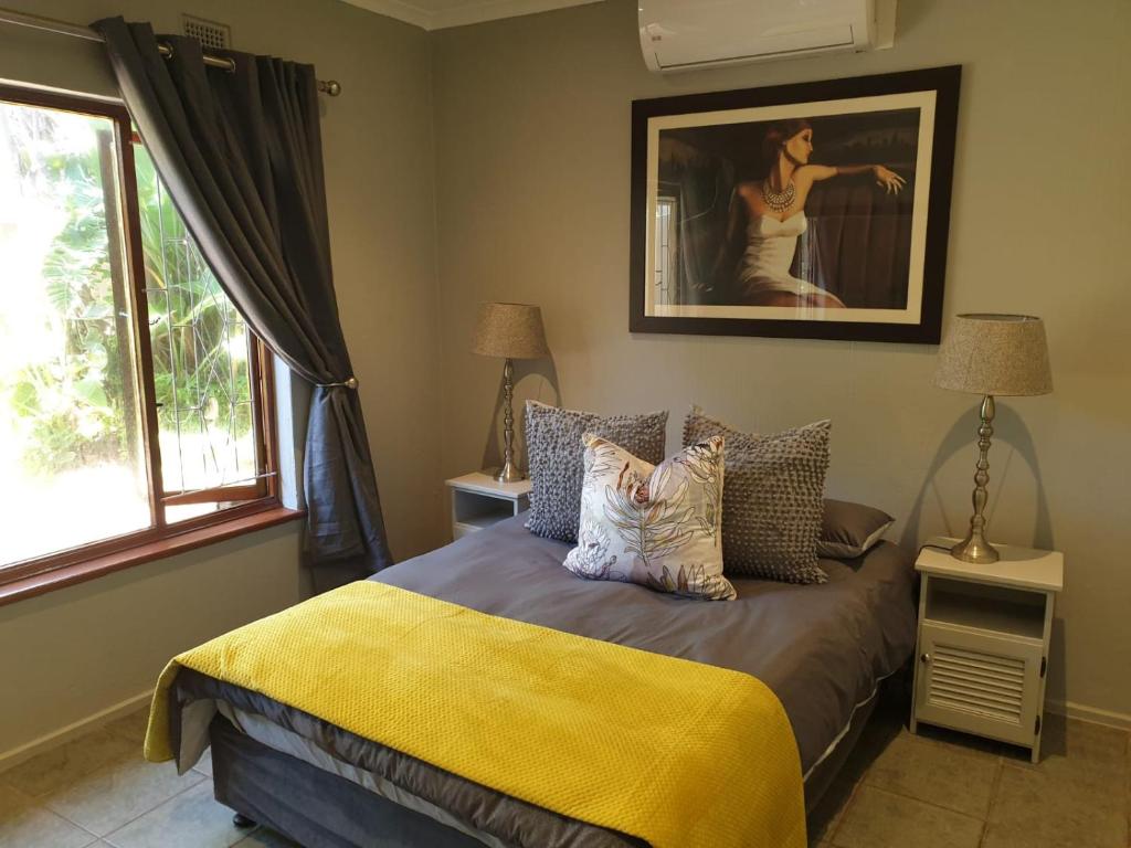 a bedroom with a bed with a yellow blanket at House Elizabeth in Scottburgh