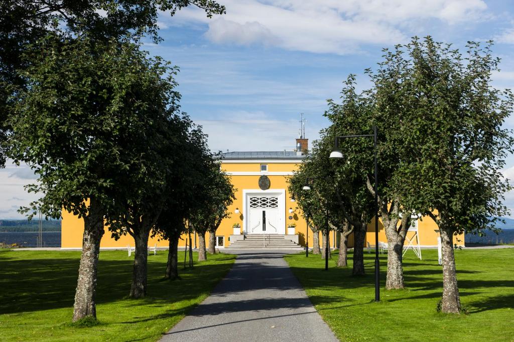 un edificio amarillo con árboles delante de él en Hotell Jeløy Radio en Moss