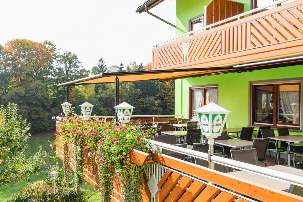 un patio con mesas, sillas y flores en un edificio en Gasthof-Pension Lamm en Görwihl