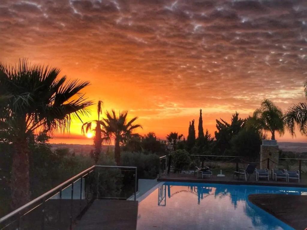 puesta de sol sobre una piscina con palmeras en Luxury Villa Albufeira, en Albufeira
