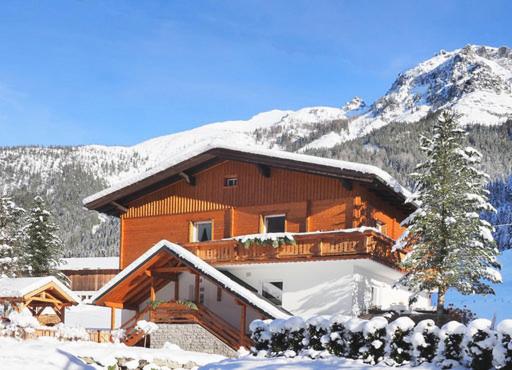 a building with snow covered mountains in the background at Ferienwohnung Alpklang in Untertauern