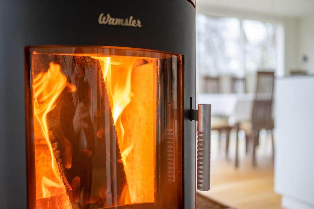 un refrigerador negro con un fuego dentro de él en Ferienhaus direkt am See - Kamin, Klima, Sauna und Boot, en Friedland