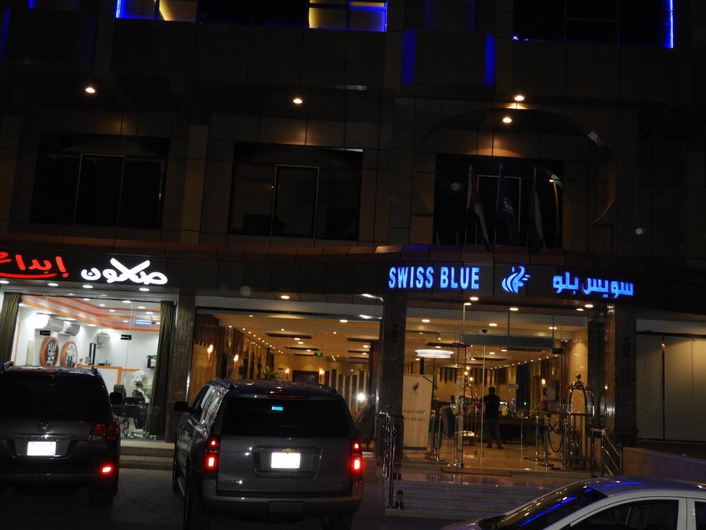 dwa samochody zaparkowane w nocy przed sklepem w obiekcie Swiss Blue Al Samer w mieście Dżudda