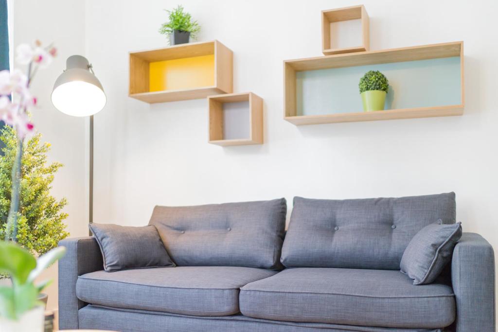 - un canapé bleu dans un salon avec des étagères dans l'établissement Grand Place Studio, à Bruxelles