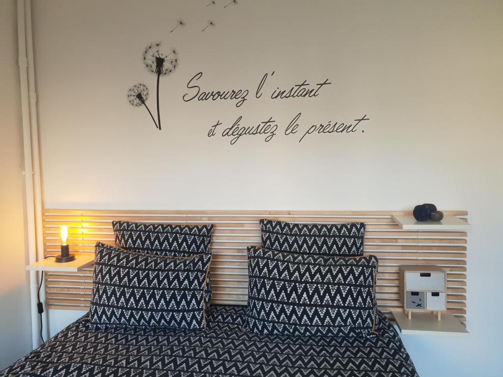 sypialnia z łóżkiem z napisem na ścianie w obiekcie LE GARDEN CENTRAL STUDIO w mieście Dinan