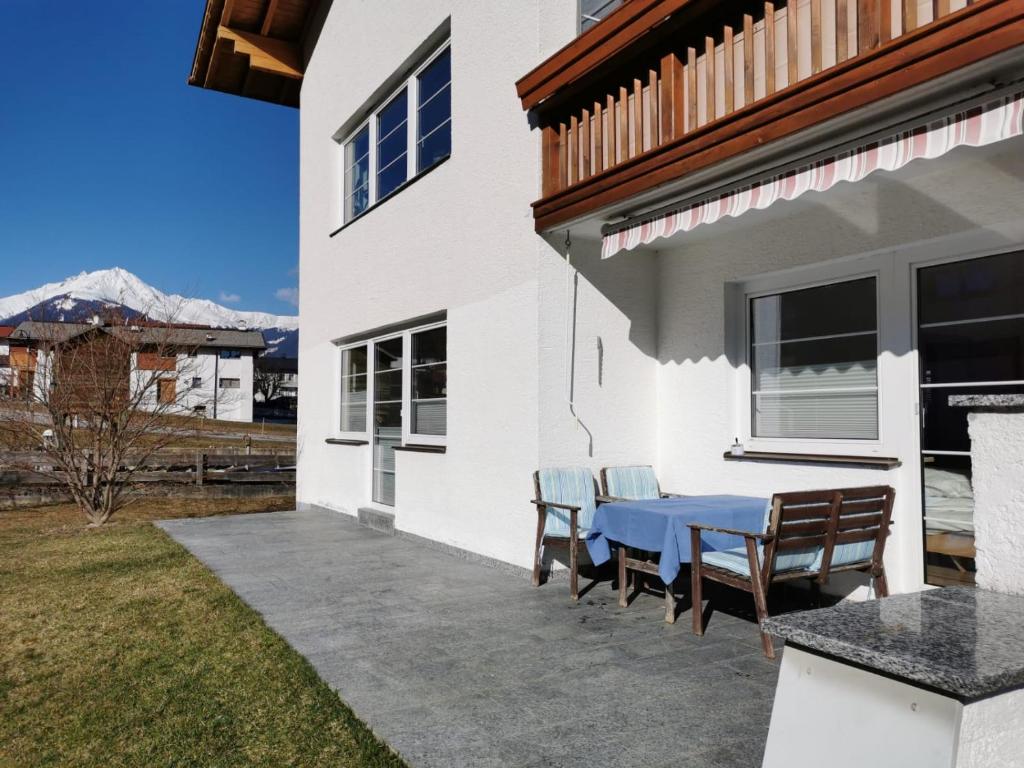 un patio con una mesa azul y sillas. en Ferienwohnung Olympia Axams en Innsbruck