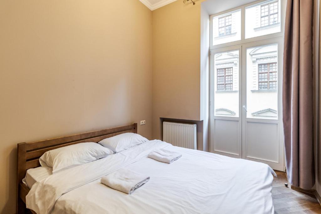 una camera da letto con un letto con lenzuola bianche e una finestra di Apartment on Stavropihiiska Street 2 a Lviv