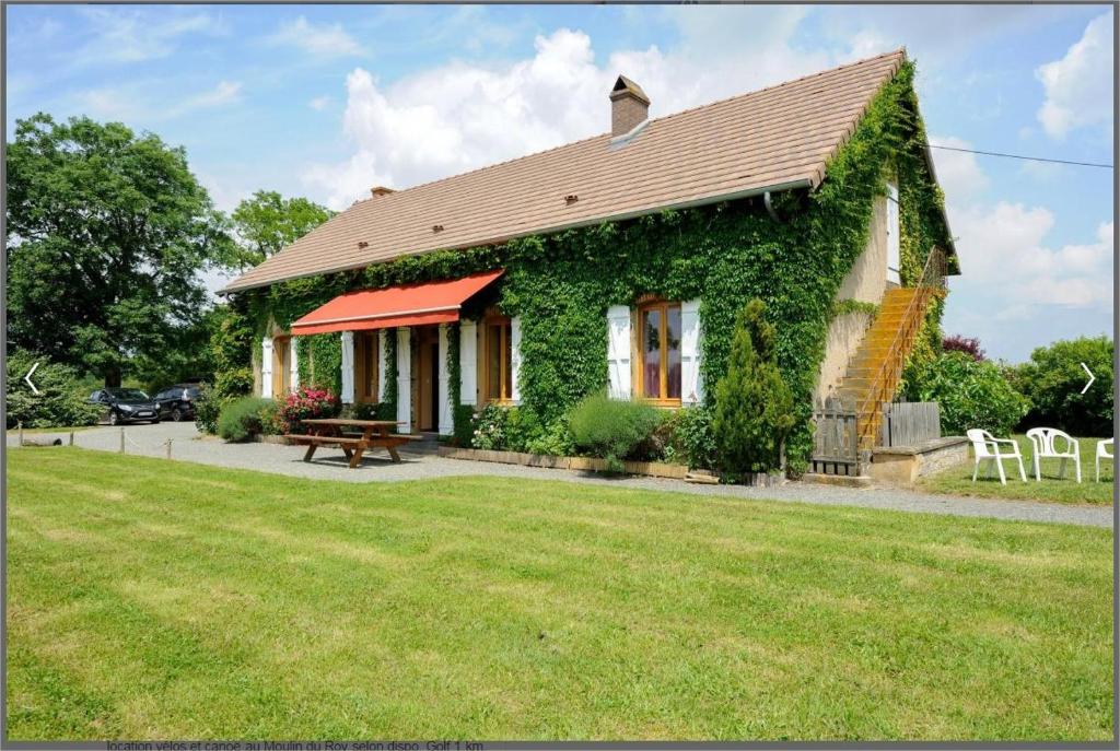 a house covered in green ivy with a picnic table at Gîte des Grands Narreaux in Bourbon-Lancy