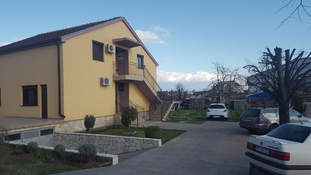 una casa con coches aparcados en un estacionamiento en Hostel Vera - Airport Podgorica, en Podgorica