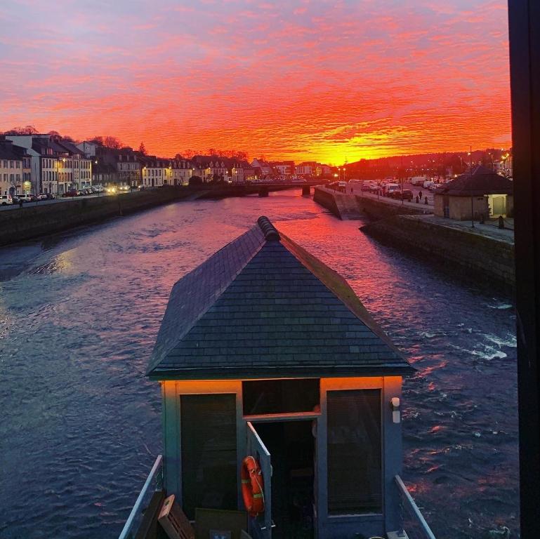 un barco en un río con la puesta de sol en el fondo en une nuit sur le pont 1, en Landerneau