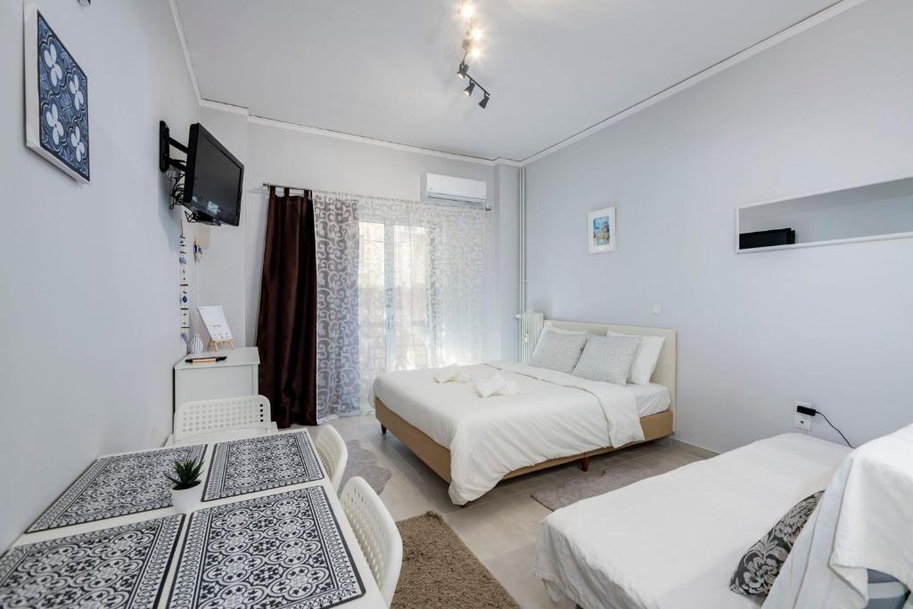 biały pokój z 2 łóżkami i telewizorem w obiekcie Beautiful studio at Panathenaic Stadium w Atenach