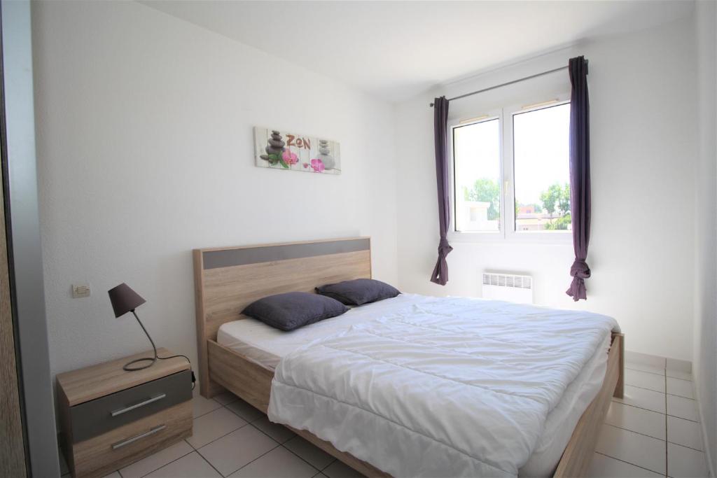 ein weißes Schlafzimmer mit einem Bett und einem Fenster in der Unterkunft VOILLIERS- T2 avec parking à 700m de la plage in Canet-en-Roussillon