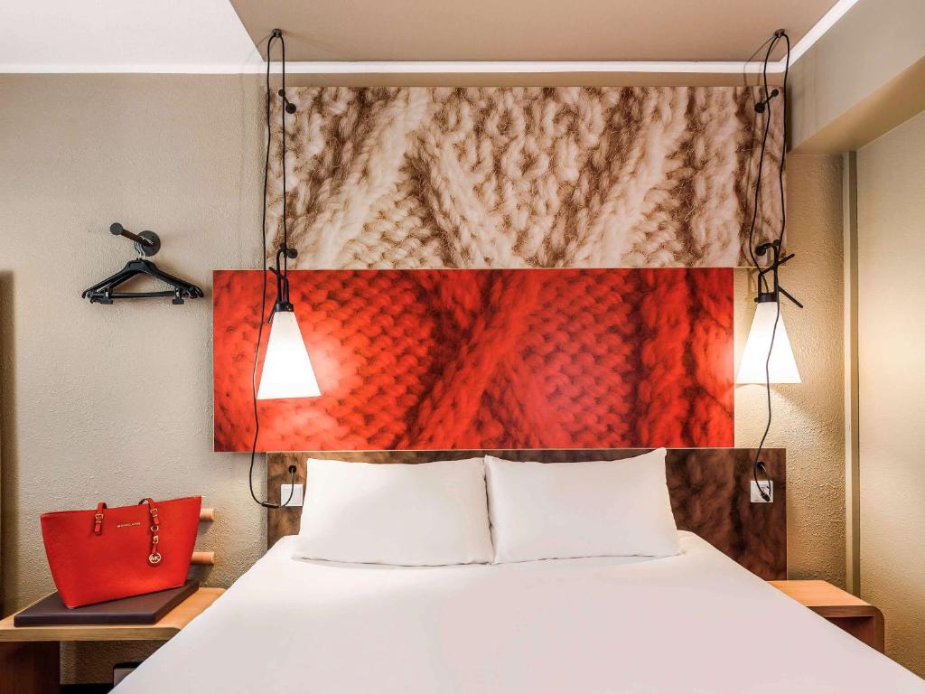 a bedroom with a bed with a red painting on the wall at ibis Hotel München City in Munich