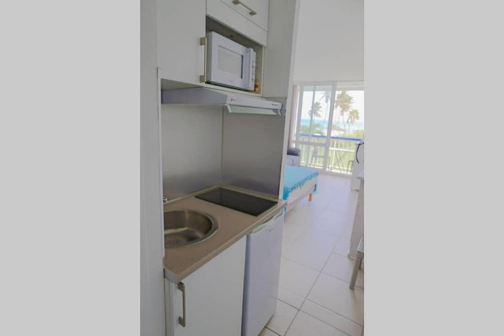 eine Küche mit einer Spüle und einer Mikrowelle in der Unterkunft AZUR - Séjour FARNIENTE en Guadeloupe! in Le Gosier