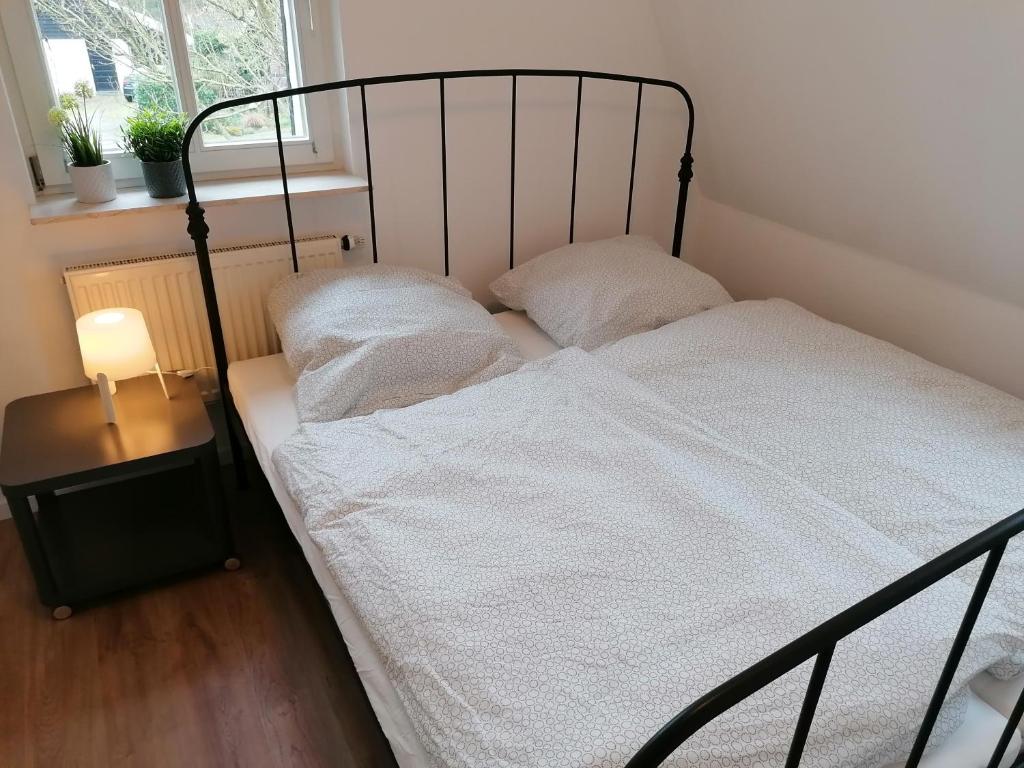 a bedroom with a black bed with white sheets at Ferienhaus Bremke am Alfsee in Rieste