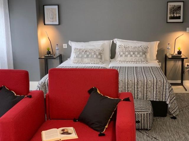 um quarto com uma cama e 2 cadeiras vermelhas em BUS STATION Suites & Studios em Coimbra