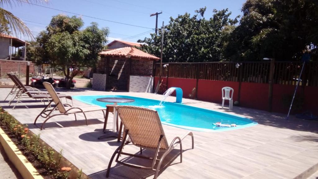 uma piscina com cadeiras, uma mesa e uma fonte em Casas Barra Sol em Barra Grande