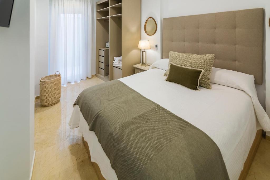 een slaapkamer met een groot wit bed met groene kussens bij Apartamento Emilo Luque Cinco in Córdoba