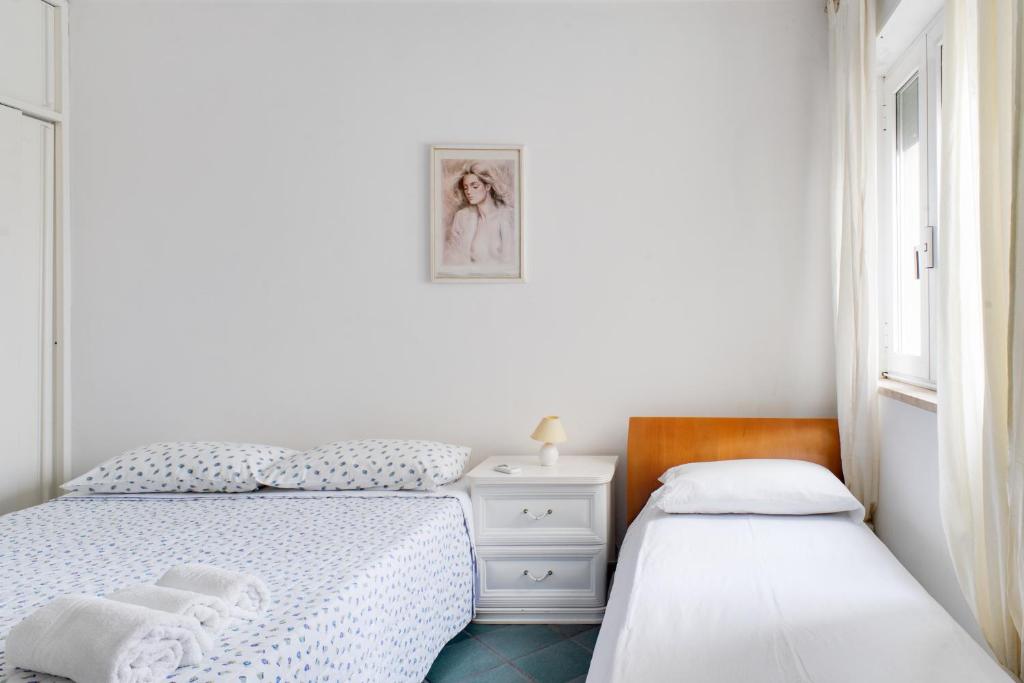 1 dormitorio blanco con 2 camas y ventana en °la casetta d'Amare°, en Torre Suda
