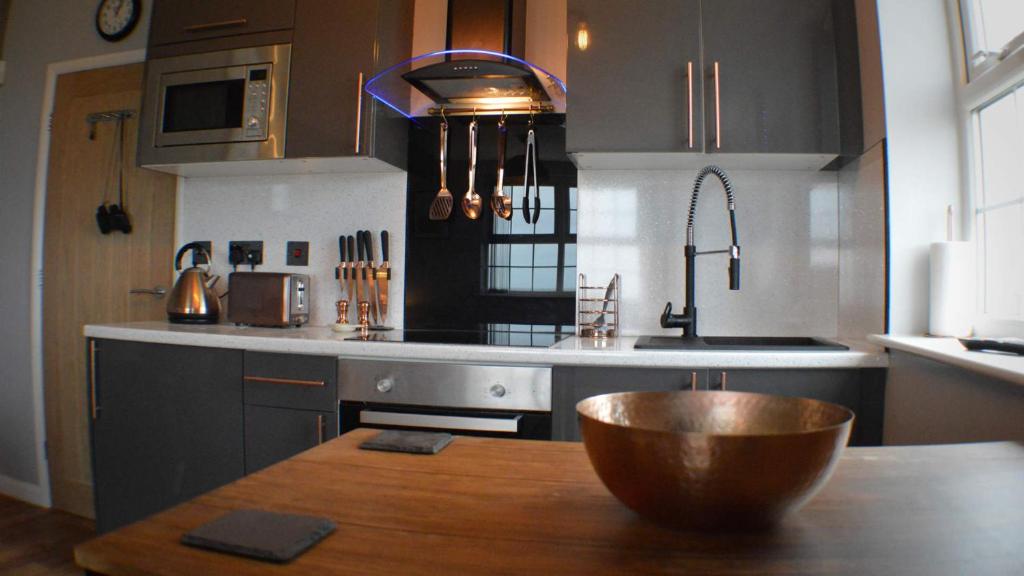 a kitchen with a wooden table and a bowl on a table at The Den Studio Apartment - Withernsea in Withernsea