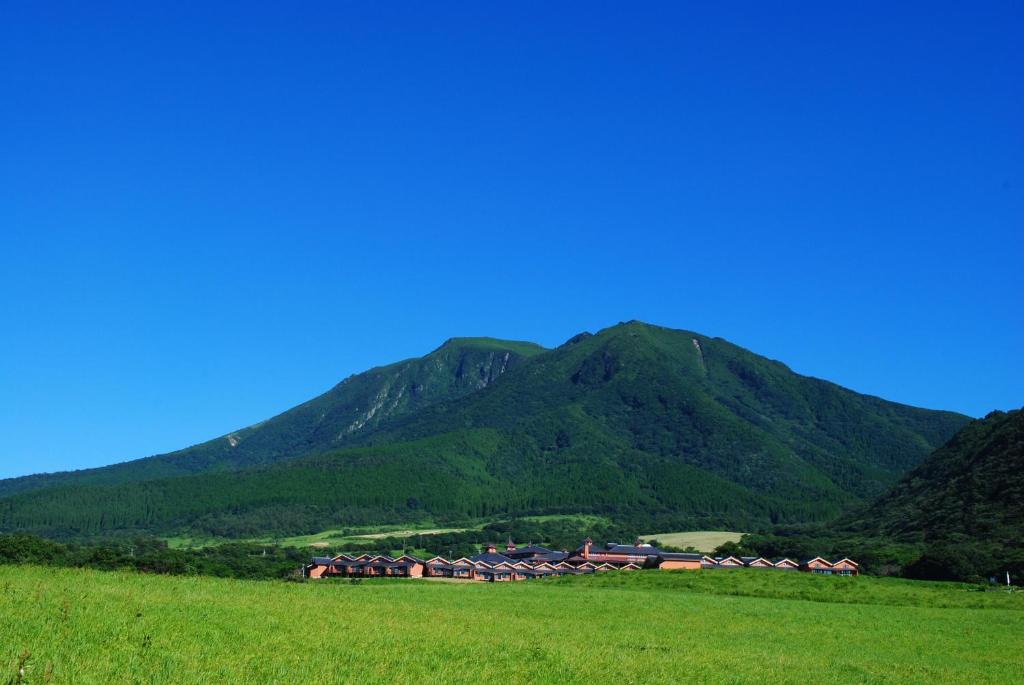 a house in a field with mountains in the background at Resonate Club Kuju in Taketa