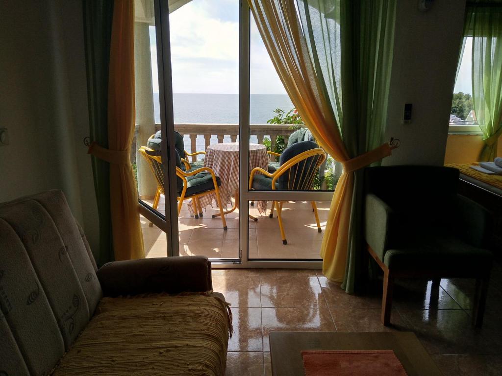 a living room with a couch and a balcony with the ocean at Majero Apartments in Utjeha