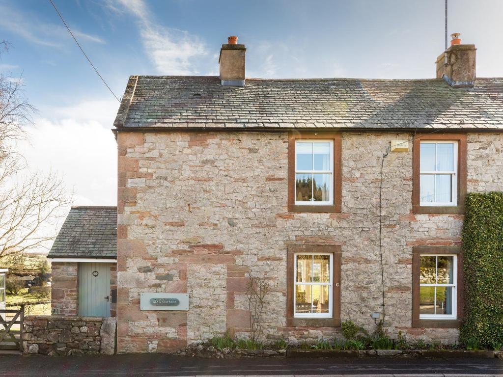 an old brick house with windows on a street at Stag Cottage in Penrith