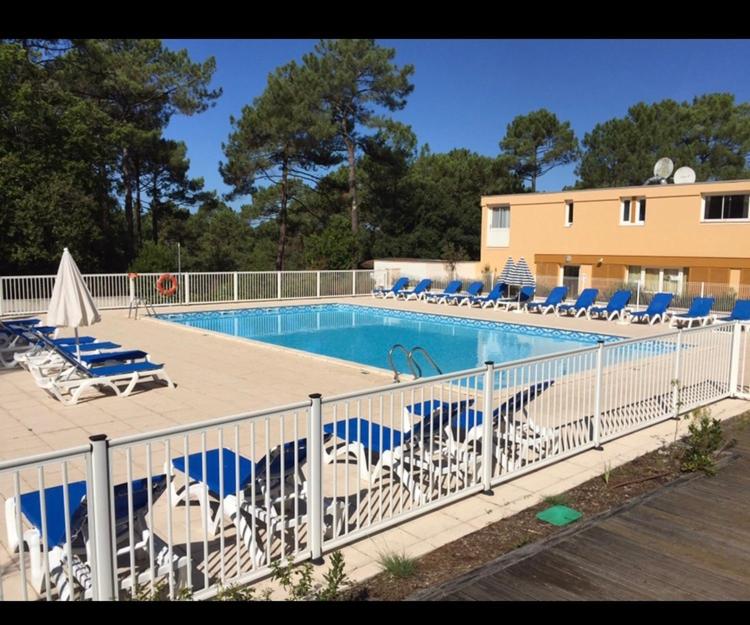 a swimming pool with chairs and a bunch ofitures at Appartement près lac et océan in Carcans