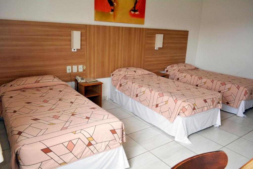 una habitación de hotel con 3 camas en una habitación en Hotel Áster, en Alagoinhas