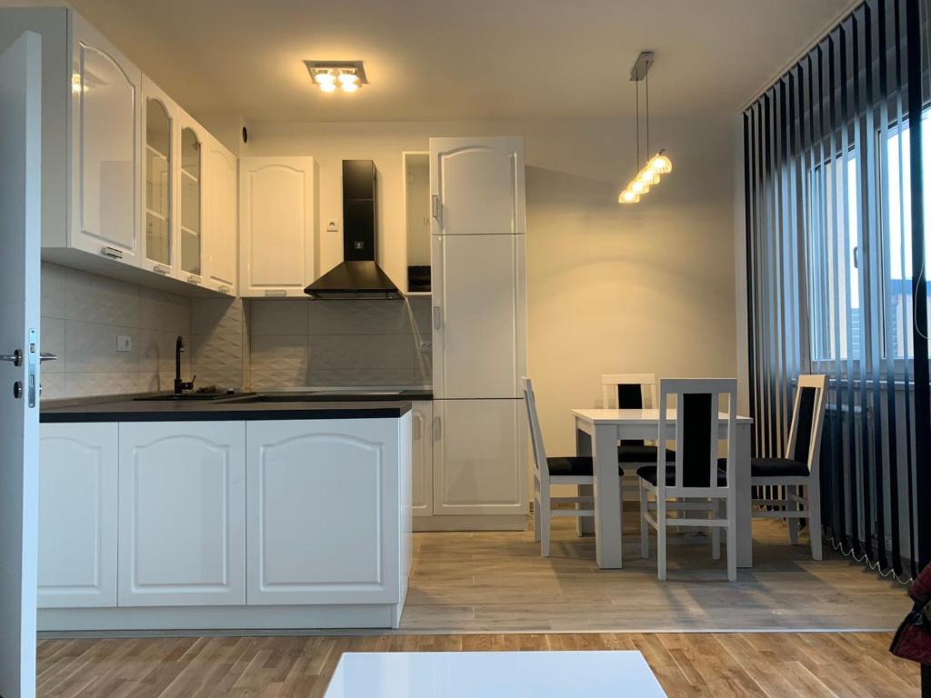 a kitchen with white cabinets and a table with chairs at Royal Residence Apartmani in Pančevo