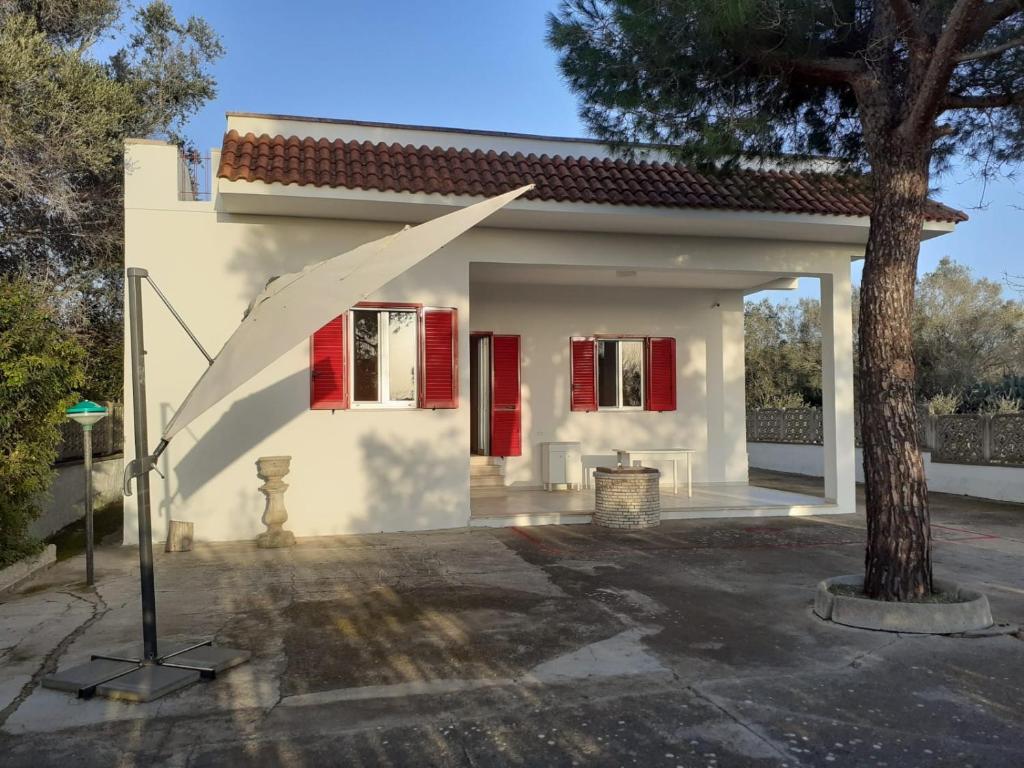 una casa blanca con persianas rojas y un árbol en Casa Vacanze "Lo Vita" Appartamento "Sara", en Galatina