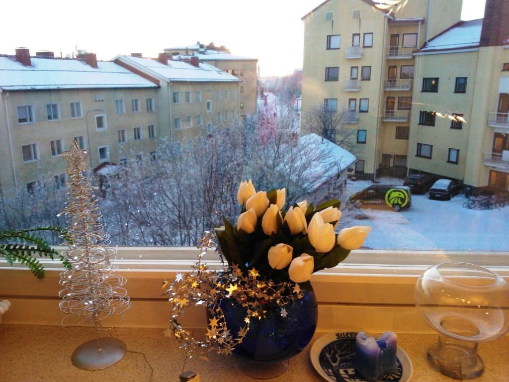 Koskikatu Apartment في روفانييمي: نافذة بها إناء من الزهور على طاولة