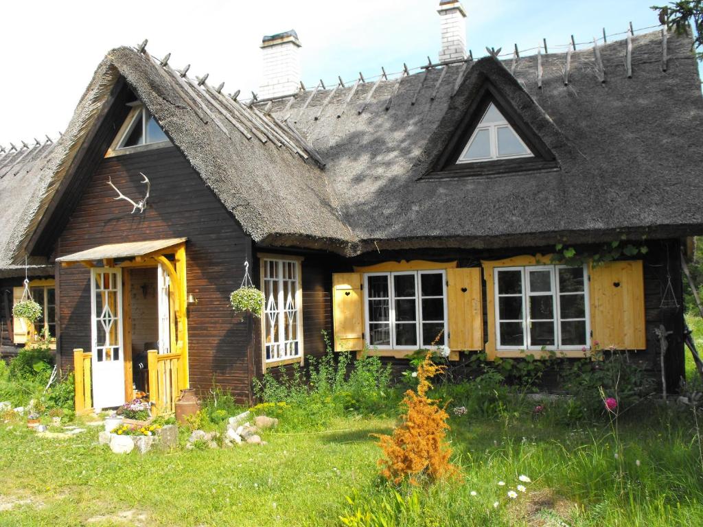 an old house with a gray roof and a yard at Rukkilille Holiday Home in Pärsama