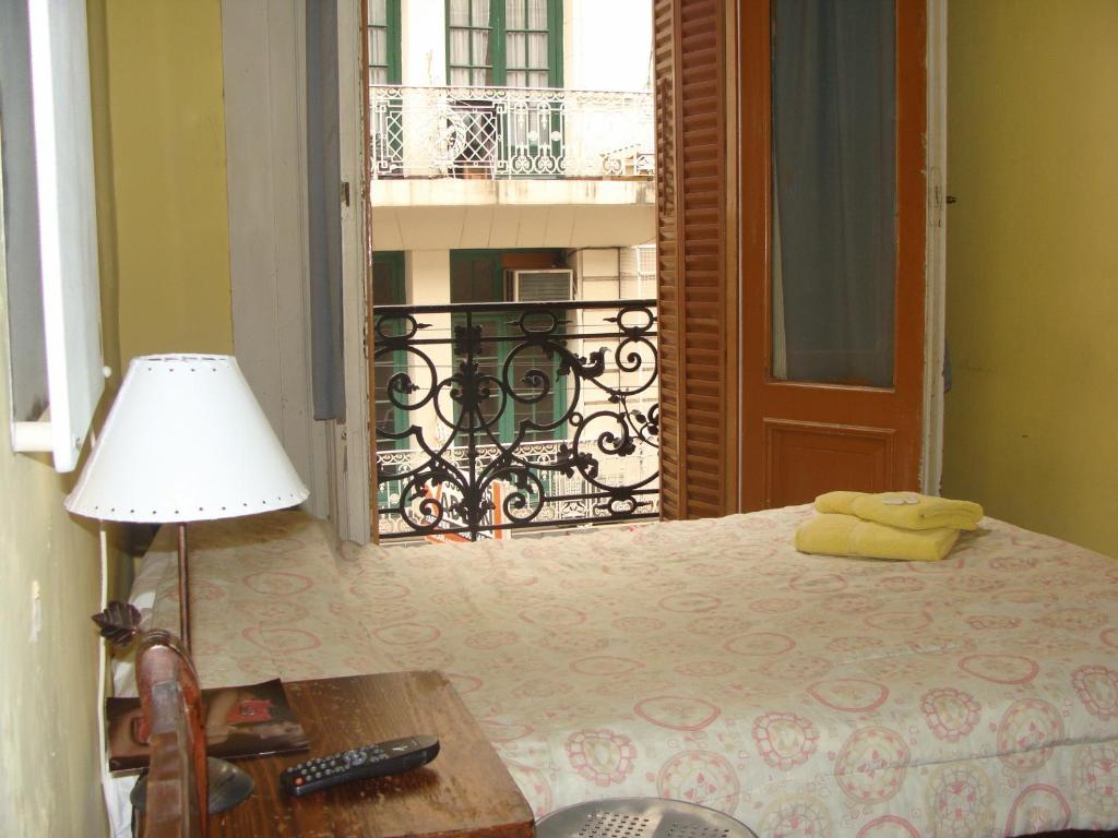 um quarto com uma cama com um candeeiro e uma varanda em Hotel O'Rei em Buenos Aires