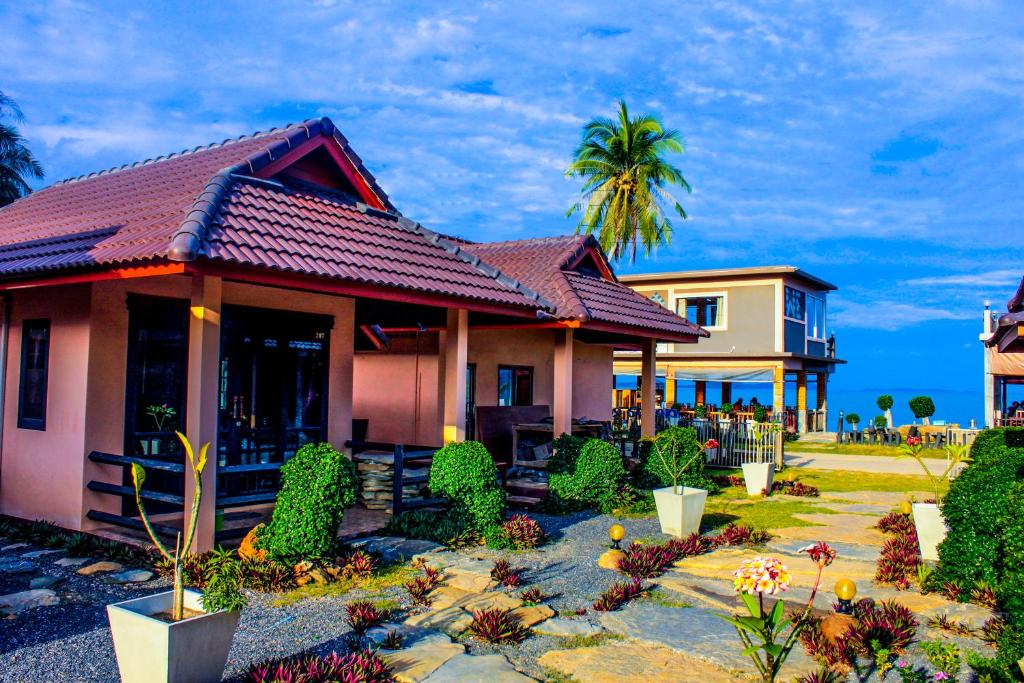 a house with a palm tree in front of it at Needa Rock Resort in Khanom