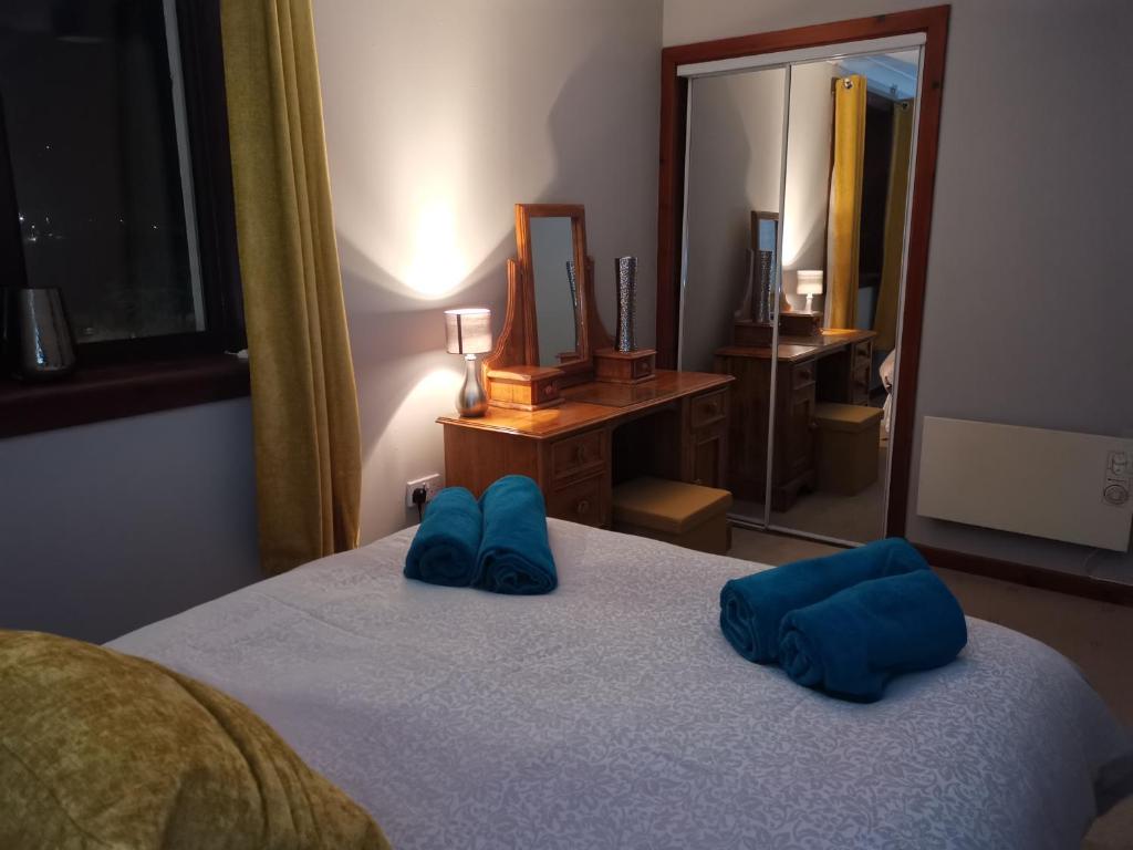 1 dormitorio con 1 cama con 2 almohadas azules en 2 Raasay Court en Portree