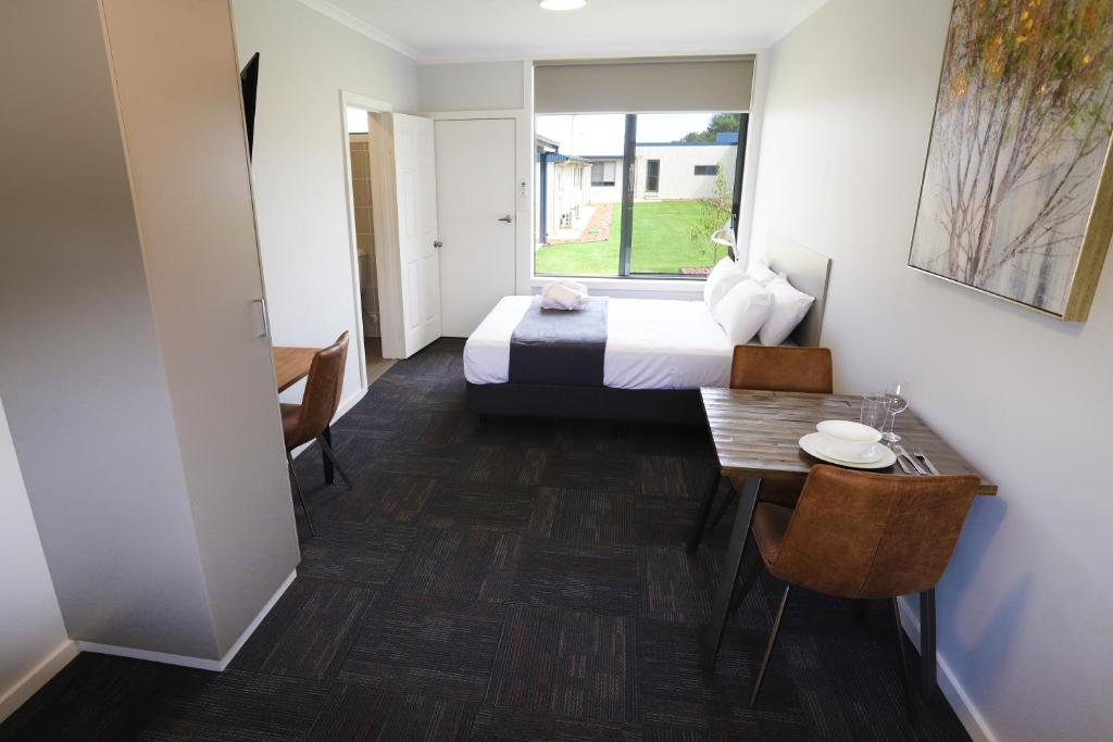 ein Hotelzimmer mit einem Bett, einem Tisch und einem Fenster in der Unterkunft Eastend Studio Apartments in Dubbo
