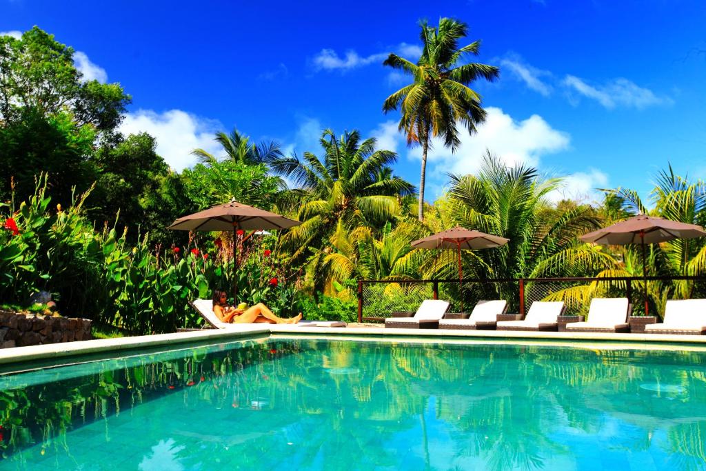 a swimming pool with chairs and umbrellas at Pousada do Vale in Fernando de Noronha