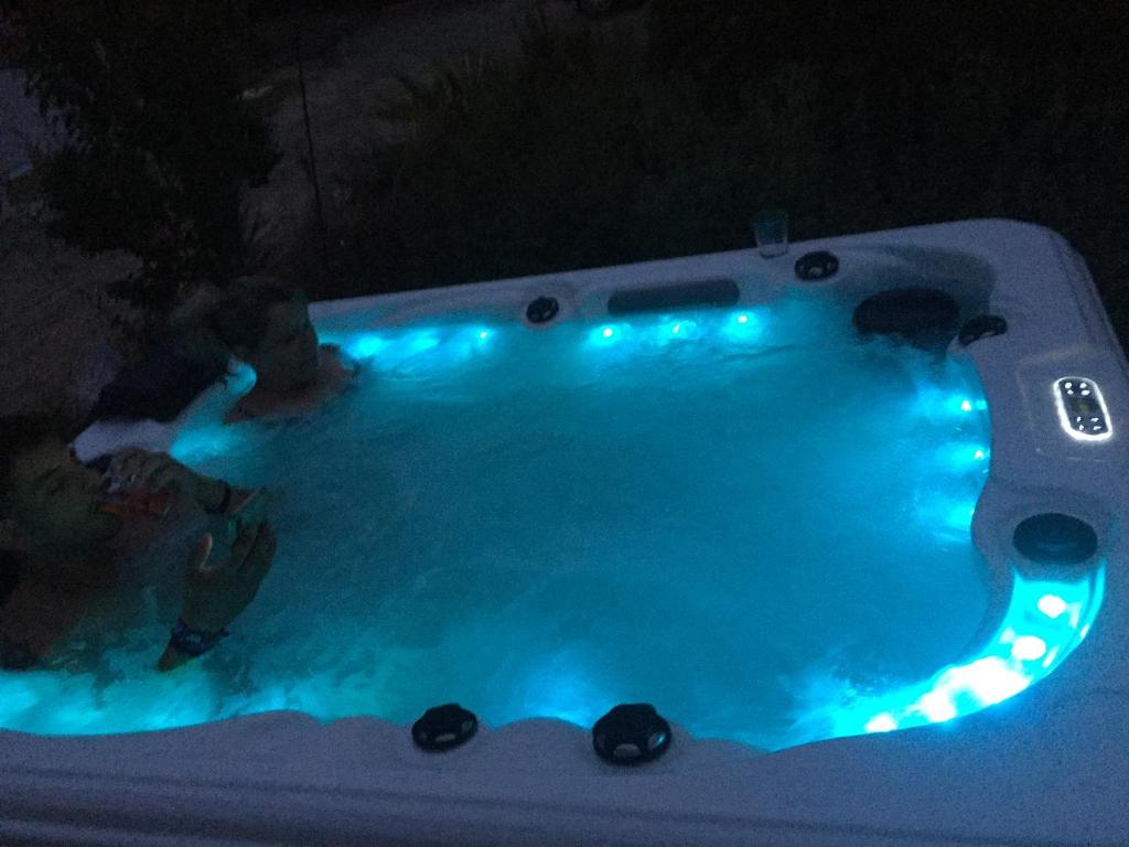 dwie osoby w basenie w nocy w obiekcie T2 climatisé baignoire terrasse Jacuzzi Piscine Sauna w mieście Launaguet